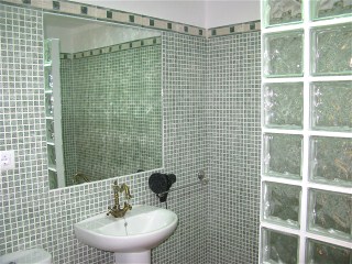 Das Bad der Ferienwohung mit grosser Spiegelwand ist mit grünen Mosaik Fliesen gestaltet