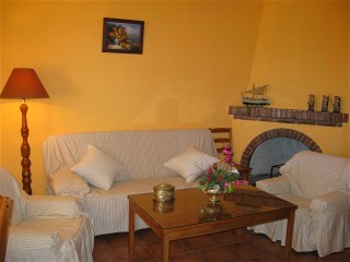 Das Wohnzimmer mit Couch und zwei Sesseln ist gelb gestrichen